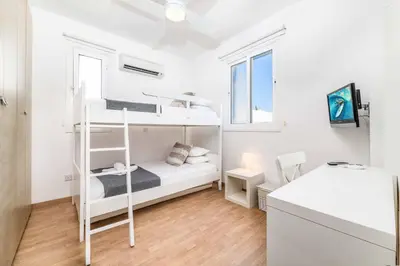 a bedroom with a white bunk bed and a desk at Villa Atlantis in Protaras