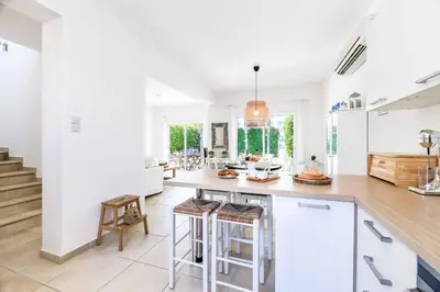 a kitchen with white walls and a island with bar stools at Villa Atlantis in Protaras