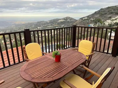 a wooden table and chairs on a deck with a view at Αετοφωλιά-AETOFOLIA in Pano Lefkara