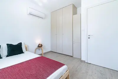 a white bedroom with a bed and a closet at Sunny & Stylish City Centre Living in Nicosia