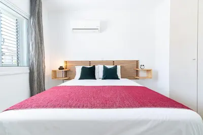 a bedroom with a large white bed with a red blanket at Sunny & Stylish City Centre Living in Nicosia