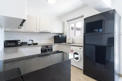 a kitchen with white cabinets and a black refrigerator at Sunny & Stylish City Centre Living in Nicosia