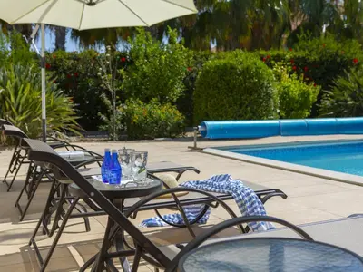 a table with chairs and an umbrella next to a pool at Pervolia Nirides Seaside Mansion 7 in Larnaka