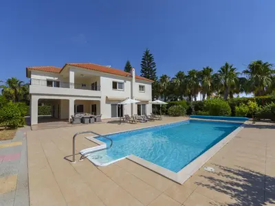 a villa with a swimming pool in front of a house at Pervolia Nirides Seaside Mansion 7 in Larnaka