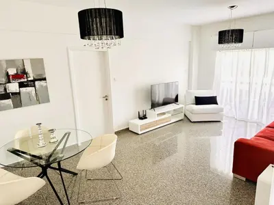 a living room with a glass table and white chairs at Charming 2 Bdr Nicosia Apt Free Parking & Wi-Fi in Nicosia