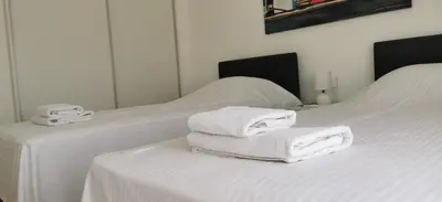 two white towels are stacked on a white bed at Charming 2 Bdr Nicosia Apt Free Parking & Wi-Fi in Nicosia
