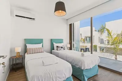 two beds in a room with a large window at Azure Leda Villa in Protaras