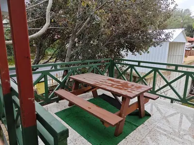 a wooden picnic table sitting next to a green fence at Kalidoniahouses in Perapedhi