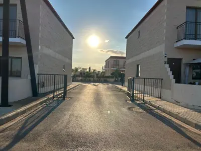 an empty street between two buildings with the sun setting at Andrea's house in Liopetri