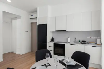 a kitchen with white cabinets and a table and chairs at Artemis 302 - Seaside Stories in Livadhia