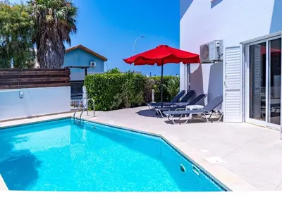 a swimming pool with a red umbrella and two lounge chairs at Anemone Seaview Villa DPS01 in Protaras