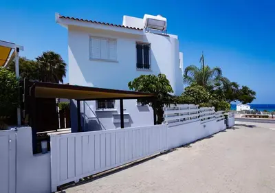 a white house with a white fence and the ocean at Anemone Seaview Villa DPS01 in Protaras
