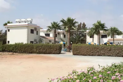 a white building with palm trees in the background at Amethyst Napa Annex Apartments in Ayia Napa