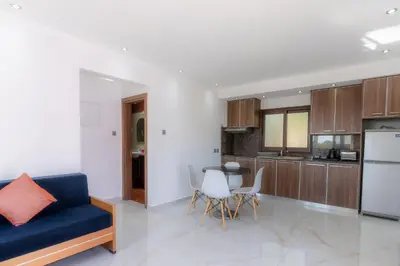 a living room with a blue couch and a kitchen at Amethyst Napa Annex Apartments in Ayia Napa