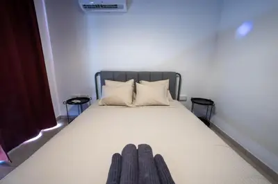 a white bed with two pillows and two tables at Penthouse, City Center, Walking to Beach in Larnaka