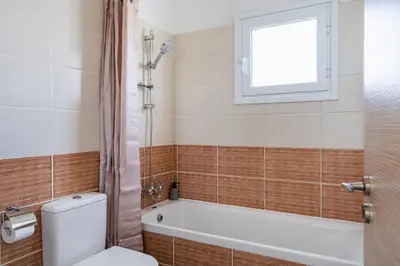 a bathroom with a toilet and a tub and a window at Phoenix 2-Bedroom Apartment in Larnaka