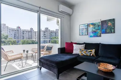 a living room with a black couch and a balcony at Phoenix 2-Bedroom Apartment in Larnaka
