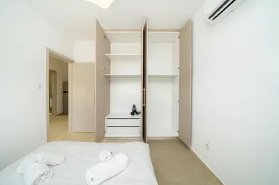 a bedroom with a white bed and white shelves at 1 bedroom flat next to university in Aglantzia