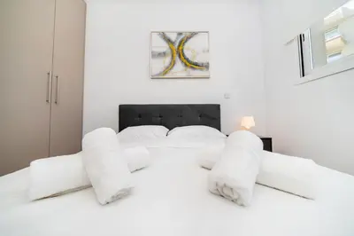 a white bedroom with a white bed with white pillows at 1 bedroom flat next to university in Aglantzia