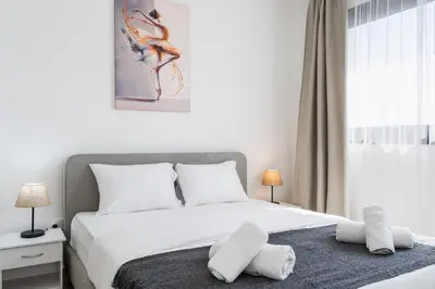 a bedroom with a bed with white sheets and pillows at Jas Living - Chic Apts & Balconies in Larnaca in Larnaka