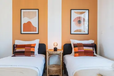 two beds in a room with orange walls at Vervana 2-Bedroom Apartment in Larnaka
