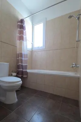 a bathroom with a toilet and a tub and a window at Chrystallia Protaras in Paralimni