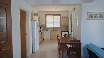 a kitchen and dining room with a table and a refrigerator at Chrystallia Protaras in Paralimni