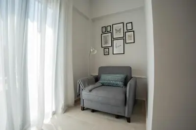 a gray chair sitting in a room next to a window at Raise Cityscape Limassol Suites in Limassol