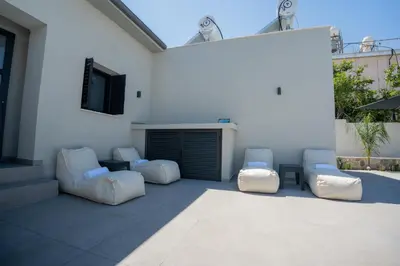 a patio with two white chairs and a building at Raise Cityscape Limassol Suites in Limassol