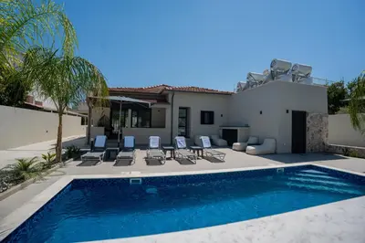 a swimming pool with chairs and a house at Raise Cityscape Limassol Suites in Limassol