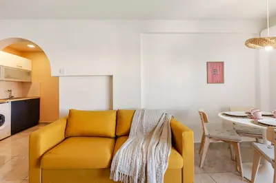 a living room with a yellow couch and a table at Kastella Blue Apartment Near Beach in Larnaka