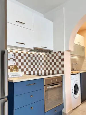 a kitchen with blue cabinets and a checkered wall at Kastella Blue Apartment Near Beach in Larnaka
