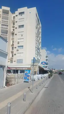 an empty city street with a large white building at Kastella Blue Apartment Near Beach in Larnaka