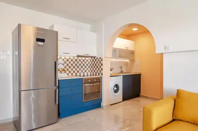 a kitchen with a stainless steel refrigerator and blue cabinets at Kastella Blue Apartment Near Beach in Larnaka