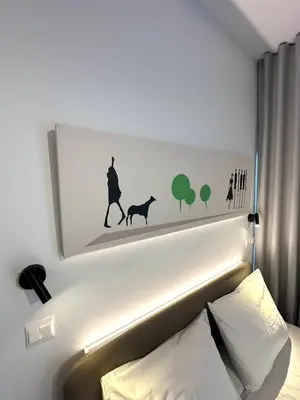 a picture of a man walking a dog above a bed at Nesseus Lux Suites - Near Unic & EUC in Ayios Dhometios