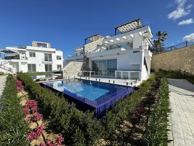 a villa with a swimming pool in front of a house at Poseidon North Ciprus, Tatlisu