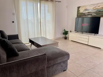a living room with a couch and a flat screen tv at Serenity in the Sun - Holiday Apt - Larnaca in Larnaka