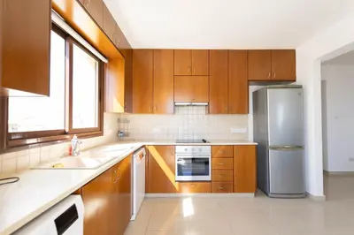 a kitchen with wooden cabinets and a stainless steel refrigerator at Spacious & Bright Apartment with Balcony in Larnaka