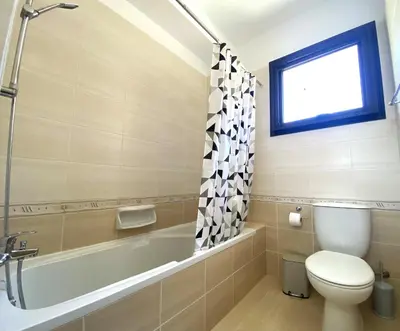 a bathroom with a toilet and a tub and a sink at Kyklades Resort & Spa in Paralimni