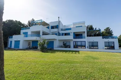 a large white house with a grassy field in front of it at Beachfront Mediterranean Escape 3bd Sea View Apartment in Pendakomo