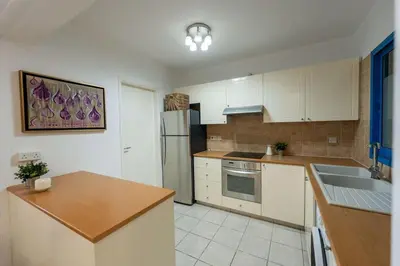 a kitchen with white cabinets and a stainless steel refrigerator at Beachfront Mediterranean Escape 3bd Sea View Apartment in Pendakomo