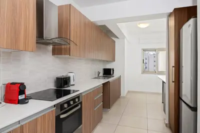 a kitchen with wooden cabinets and a red appliance at Downtown Sea View Penthouse in Larnaka