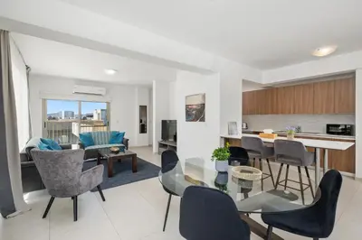 a kitchen and living room with a glass table and chairs at Downtown Sea View Penthouse in Larnaka