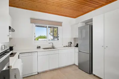 a kitchen with white cabinets and a wooden ceiling at Shoreline Beach House in Larnaka