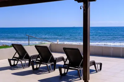 a table and chairs on a patio overlooking the ocean at Shoreline Beach House in Larnaka