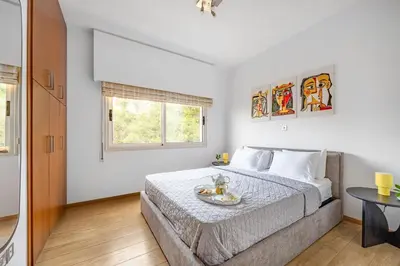 a white bedroom with a bed and a table at Lena Court - Spacious 3bdr, City Views in Limassol