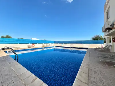 a swimming pool with blue water in front of a building at STAY Paradise Apartment in Protaras