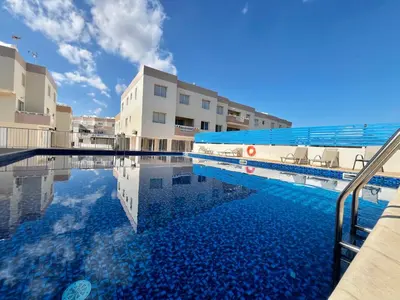 a swimming pool with chairs next to a building at STAY Paradise Apartment in Protaras
