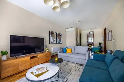 a living room with blue couches and a large tv at Berengaria Court - Sea Views 2bdr Apartment in Limassol