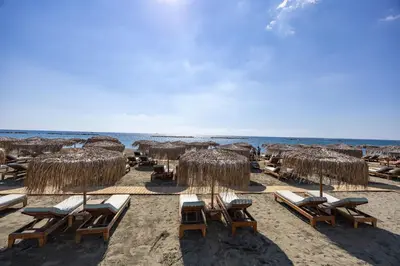 a beach with chairs and straw umbrellas and the ocean at Berengaria Court - Sea Views 2bdr Apartment in Limassol